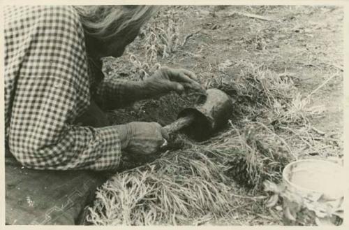 Navajo woman applying pinon gum to a cooking pot after firing