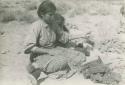 Navajo woman spinning yarn, with child sitting next to her