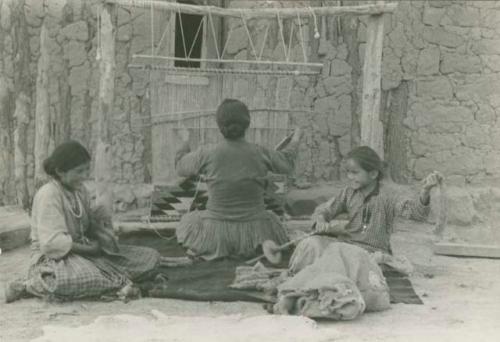 Navajo women and girl weaving and spinning