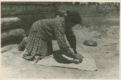 Navajo woman preparing paste, grinding the clay