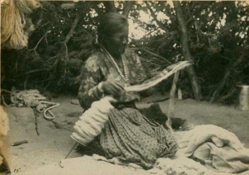 Woman spinning wool into uniform strips to be used in blanket making