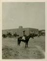 Navajo man on horseback, with building in background