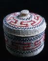 Covered spruce root basket (twined) with red and black false embroidery designs.