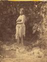 Ka'-ni. Woman standing near the woods