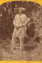 Man standing and holding arrow. Nun-A-Gun-Tits tribe