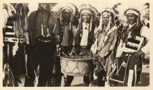 Several men in headdresses; some appear to be playing a drum