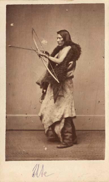 Studio portrait of man with bow and arrow posing