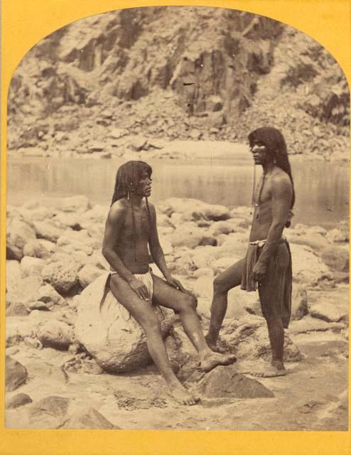 Two men, one seated on rock