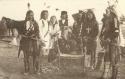 Group of men, one plays a drum which sits in the center