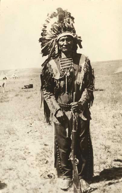 Man in feathered headdress with rifle