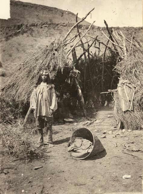 Boy standing outside brush hut