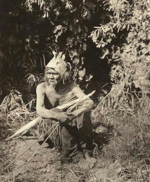 Man seated on ground, holding arrows