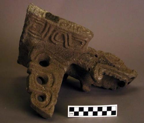 Fragment of carved stone metate, with alligator-serpent head.  One support. Curv