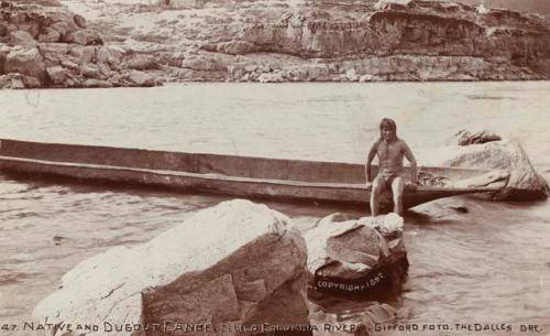 Man sitting on edge of dugout canoe