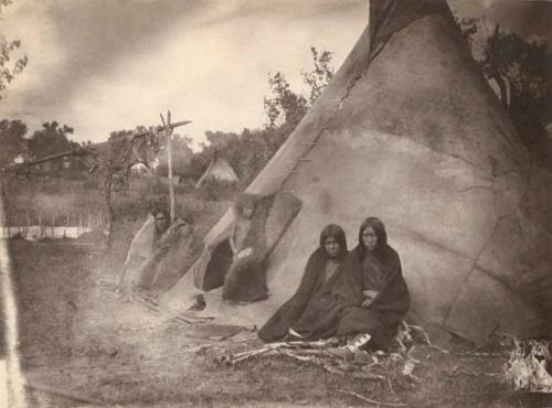 People seated outside tipi