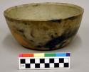 Ceramic bowl, complete, micaceous slip, fire marks around base.