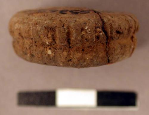 Spindle whorl. discoidal, thick, single perforation in center. medially grooved