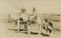 Three Blackfoot Indians on horseback with a travois