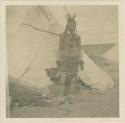 Crow Indian standing in front of tepee at Billings, MT