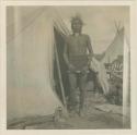 Crow Indian standing by tent at Billings, MT where they came from their reservation to trade and dance