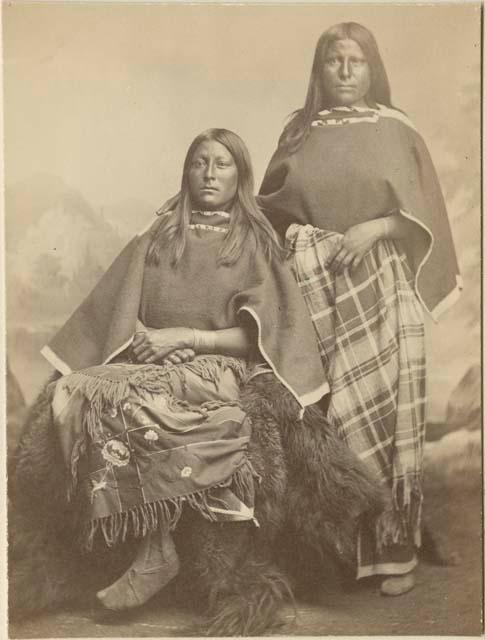 Full-length studio portrait of two women, one seated