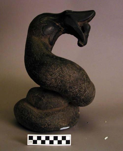 Ground stone snake effigy, black, textured surface