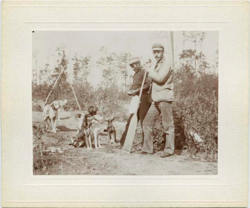 Two men holding oars surrounded by dogs, Basswood Lake.