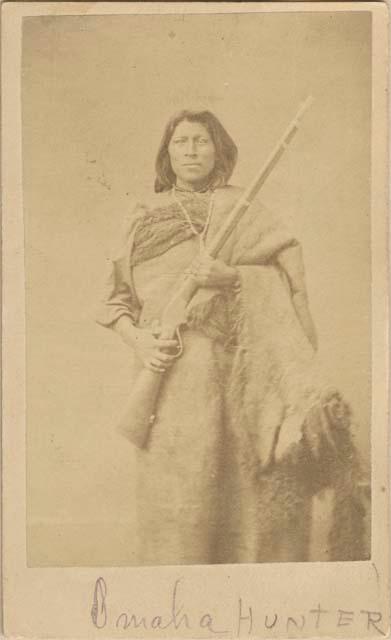 Studio portrait, man with rifle in both hands; Omaha hunter