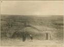 Omaha man and woman in front of an earth lodge, superimposed on landscape photograph