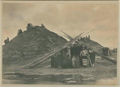 People standing before Pawnee lodge