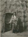 Young woman standing by doorway of grass house