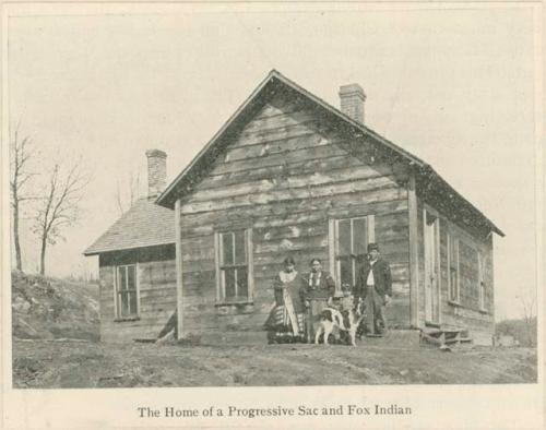 Meskwaki family standing in front of their house