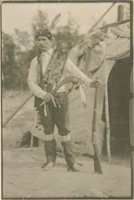 Chief Sabatis standing in front of a wigwam