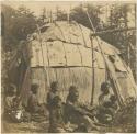 Saulteaux family in front of a birch bark hut