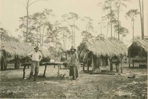 Man and woman standing around central table in camp