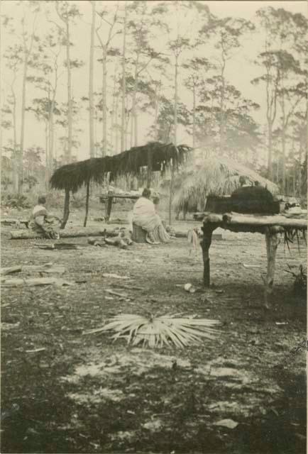 Women sitting beside hut