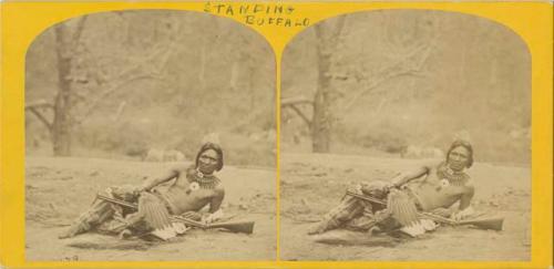 Portrait of Standing Buffalo, reclined on ground with gun on his lap