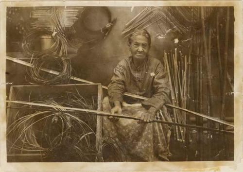 Clara Dardin at work splitting canes from which she made baskets