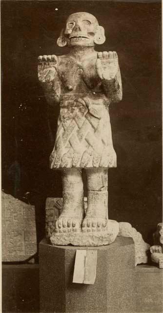 statue - human-like figure, raised palms, skirt of snakes (?)