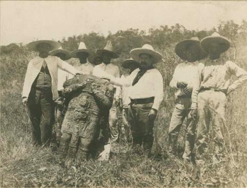 Men standing beside a part of an excavated stone monument