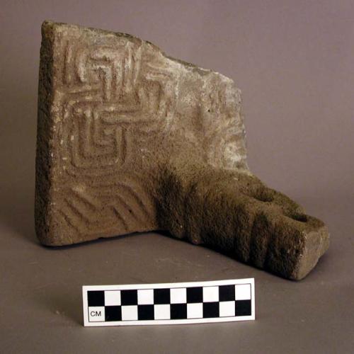 Fragment of carved stone metate, with one support.  Curvilinear motifs.  6 1/4"h