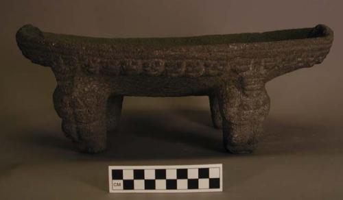 Stone metate, with 4 figural supports.  Decorative rim.  17" w.