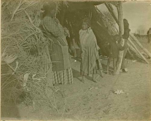 Navajo women and children in front of hogan