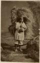 Studio portrait of Maya man holding a large bundle of grass