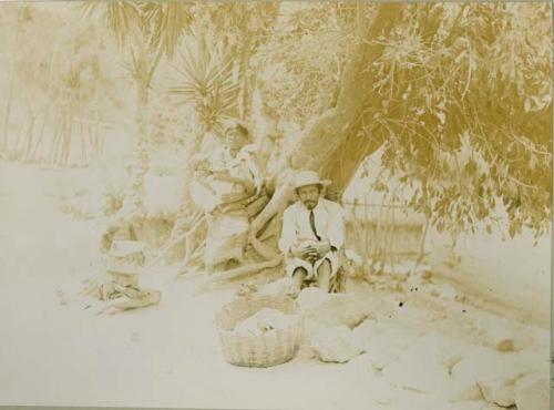 Maya man, woman and children sit beneath a tree