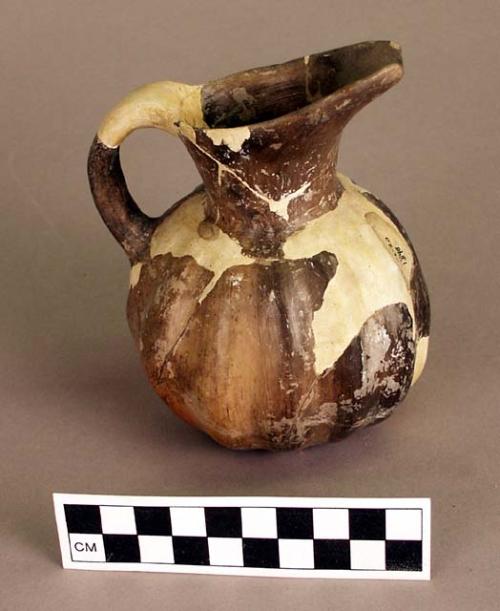 Restored grooved brown pottery pitcher.