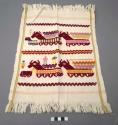 Servilleta, white ground, fringed two sides, red brocade animal figures, zigzags, people