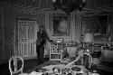 Man on telephone and woman at table in ornate room