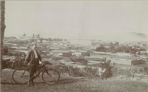 Man standing with bicycle, city behind him