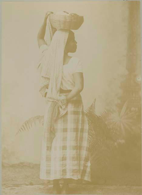 Studio portrait of Maya woman holding basket on head